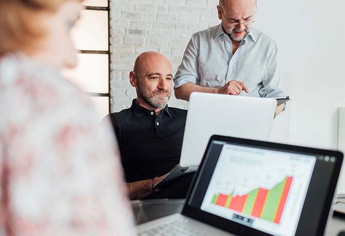 Gestores analisando gráficos de desempenho em reunião corporativa com foco em metas, produtividade e melhoria contínua